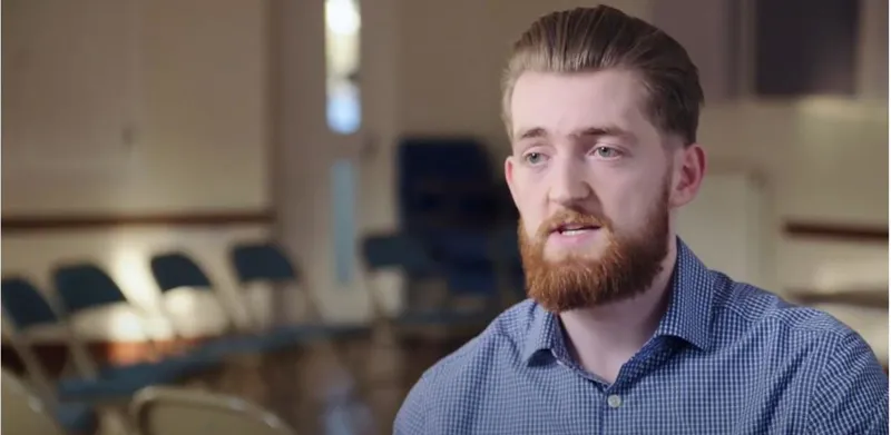 Aaron talking to camera in a hall