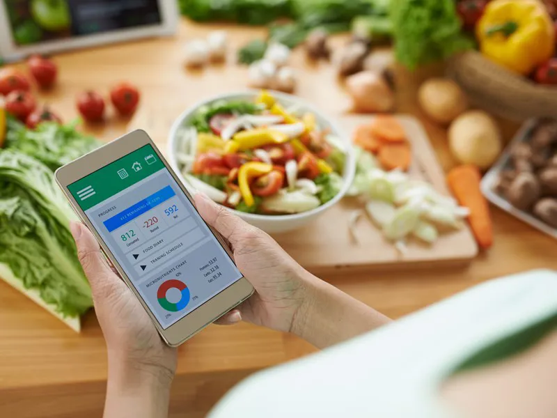 Calorie tracking app on a phone beside fresh vegetables