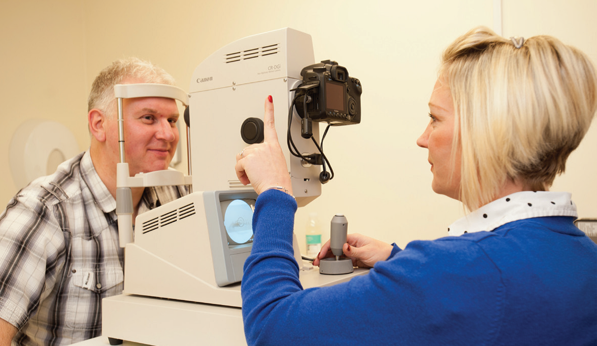 A screener taking a photograph of the back of a patient’s eye with a retinal camera