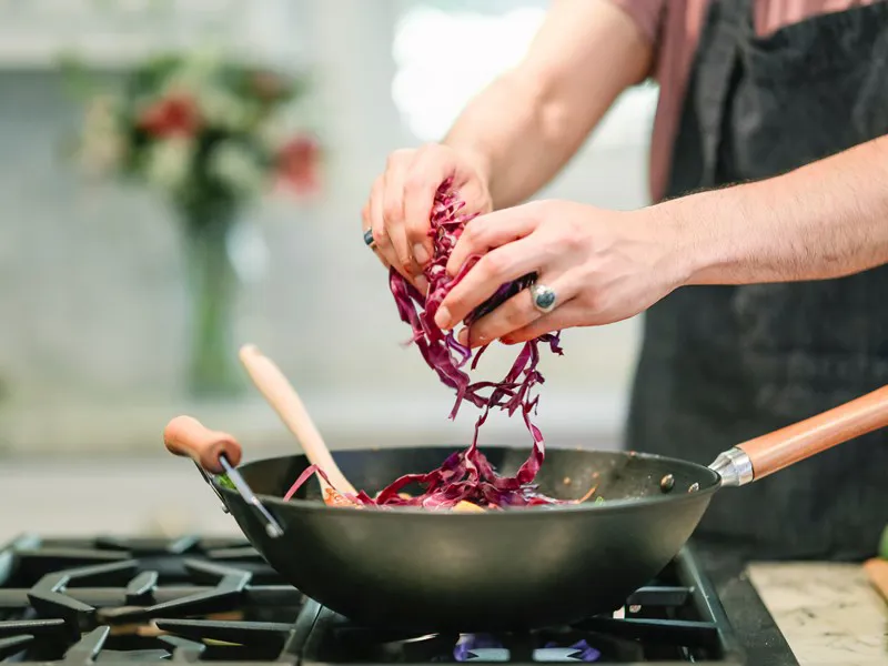 Cook adding red cabbage to a wok