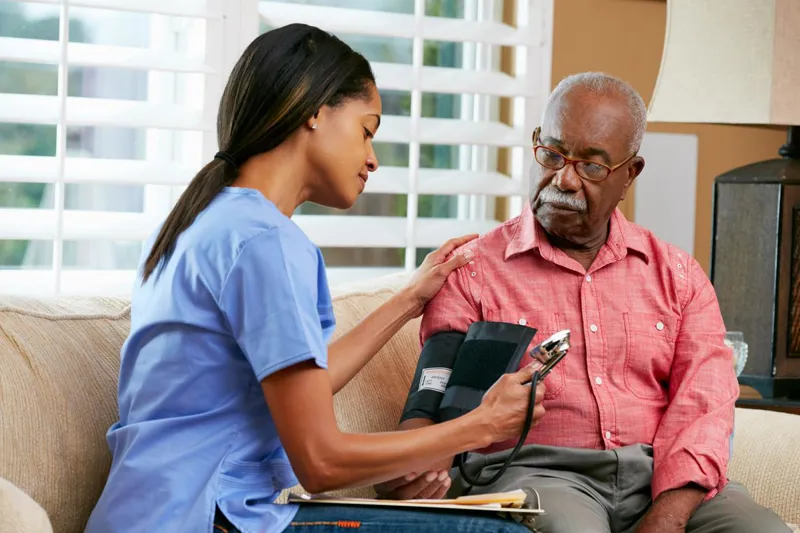 Nurse checking an older man's blood pressure at home