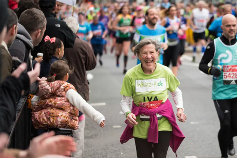 An older woman smiling as she runs in a marathon
