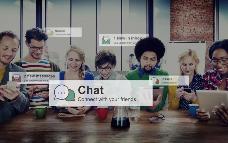 Group at a table using laptops and tablets with chat notifications