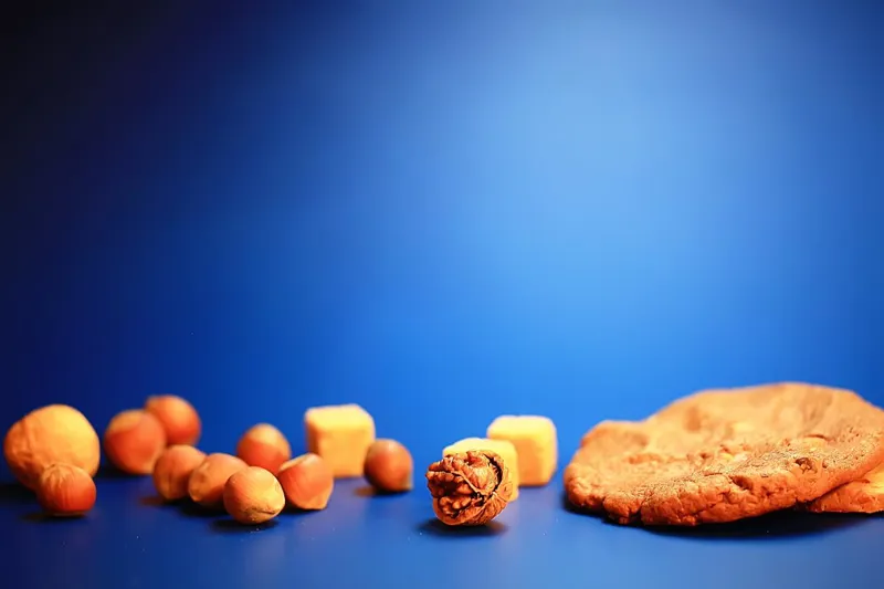 Hazelnuts, a walnut, fudge and a cookie on a blue background