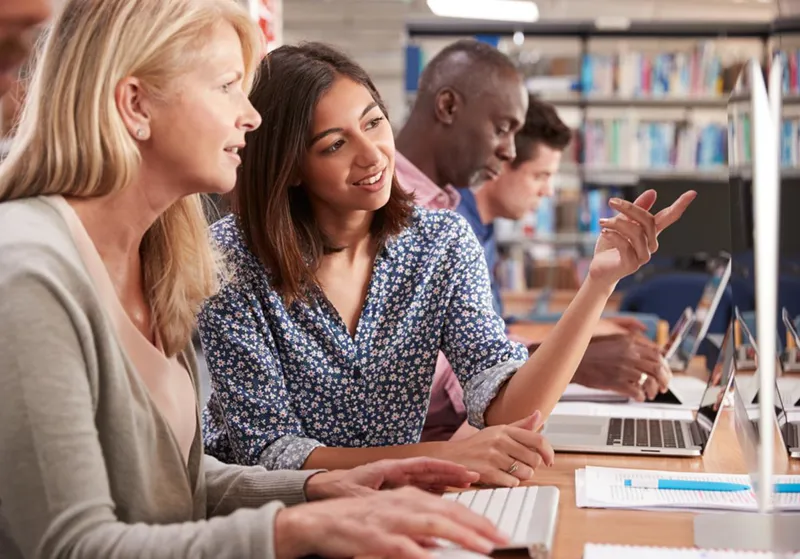 Adults learning together at a computer class