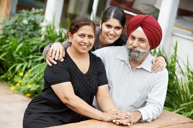 A Sikh family of three sitting together in a garden