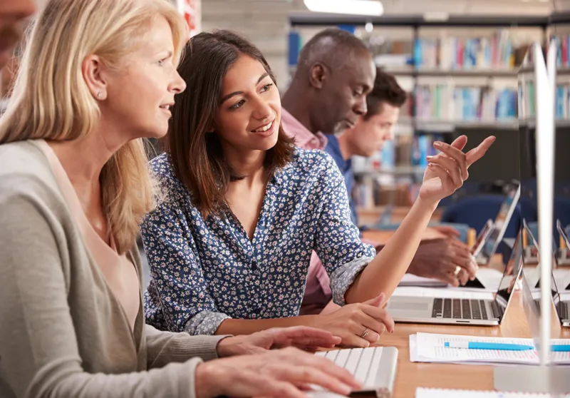 People learning together at laptops in a library